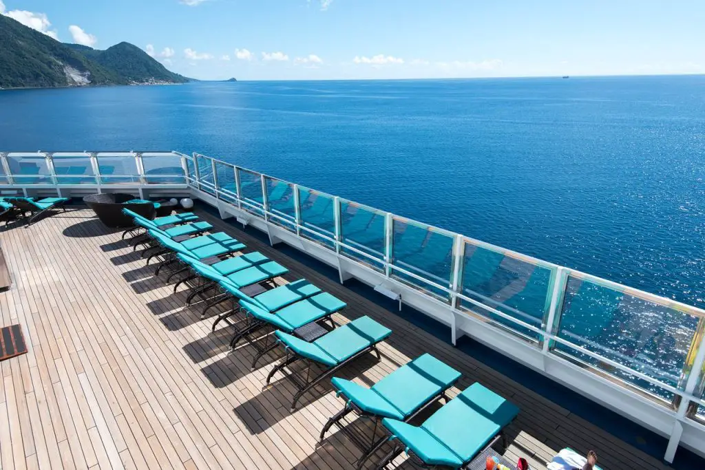 padded teal loungers on cruise deck overlooking ocean