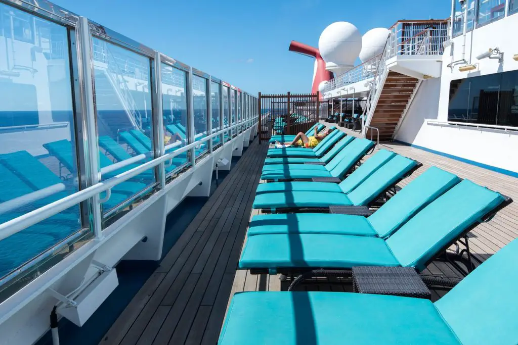 padded teal loungers by glass window on cruise ship