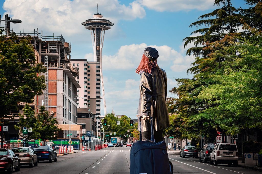 woman exploring seattle with luggage by space needle