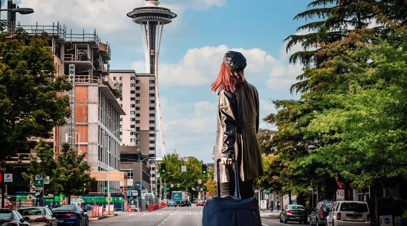 woman exploring seattle with luggage by space needle