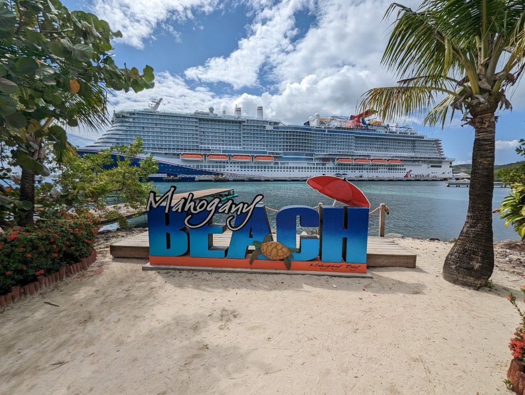 mahogany beach sign in front of carnival celebration