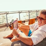 man reading paper on a cruise ship