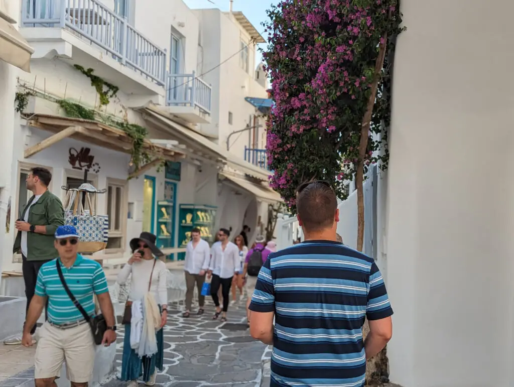 man walking streets of mykonos with flowers