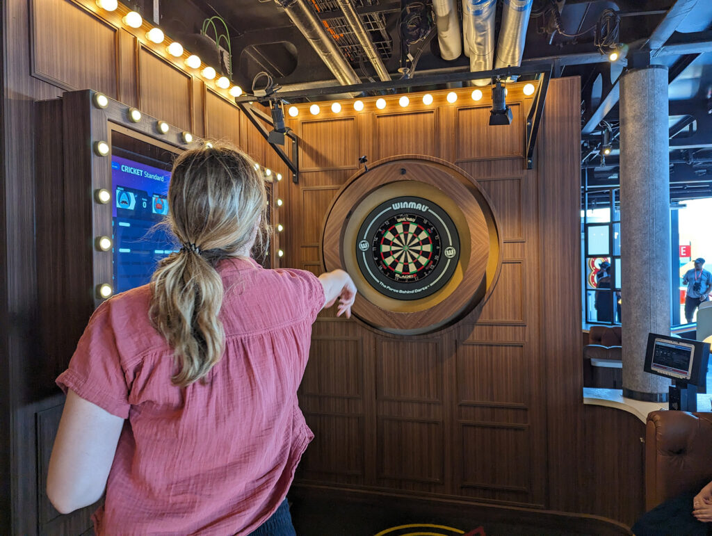 woman throwing dart at dart board on cruise ship