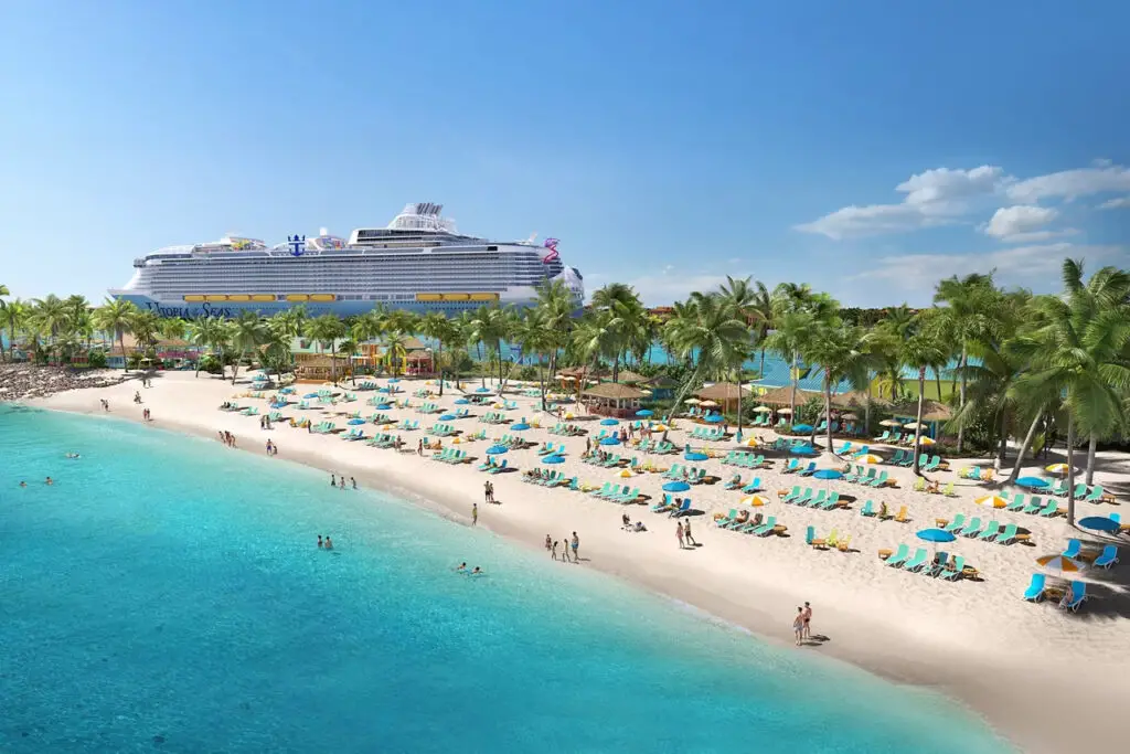 beach with loungers in front of a cruise ship